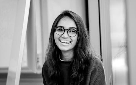 Smiling young female professional wearing glasses in an office setting, indicative of the expanding community of UX design practitioners.