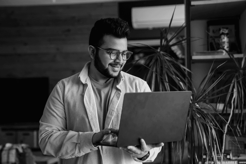 Man in glasses enthusiastically working on his laptop in a lively Sydney workspace.