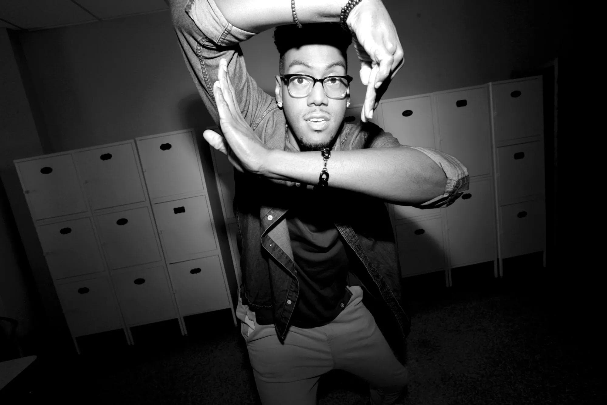 Man in a casual outfit stretching in a locker room, taking a break from learning at a New York City coding bootcamp.