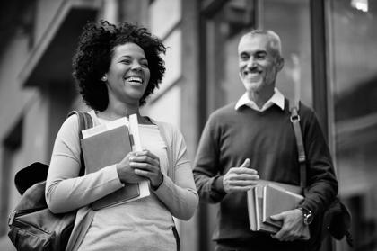 Happy mid adult African American students and her mature friend having fun while going to a library to study.