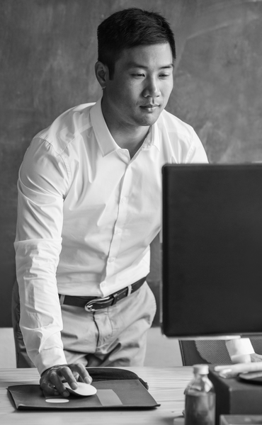 Asian businessman standing at his desk working on a computer