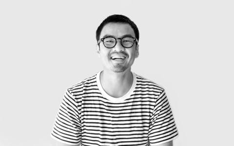 Smiling Singaporean web developer in casual attire programming with React JS in a modern co-working space.