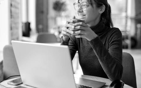 Woman enjoying coding on laptop in New York cafe during JavaScript workshop break