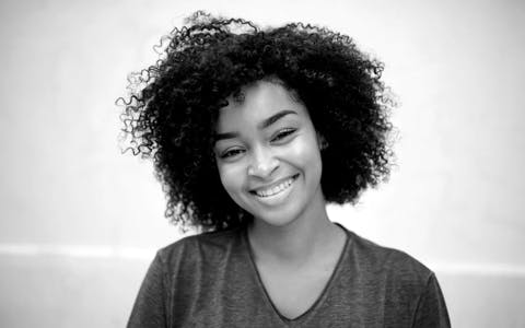 Young London woman with curly hair smiling confidently, representing the diverse and successful alumni network of the GA design program.