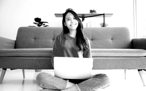 Young London woman working on a UX design project on her laptop while sitting comfortably at home, demonstrating the adaptability of online design education.