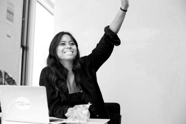 woman in black shirt raising hand and smiling